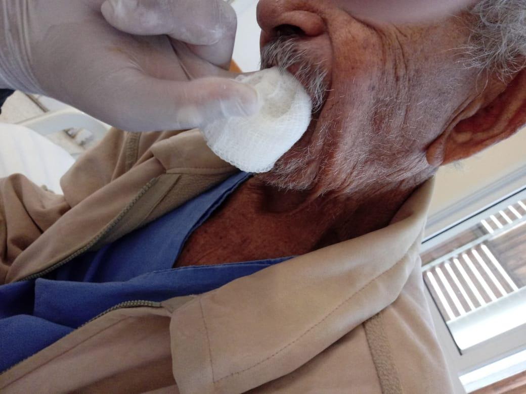 Imagem representando um senhor recebendo curativo na boca