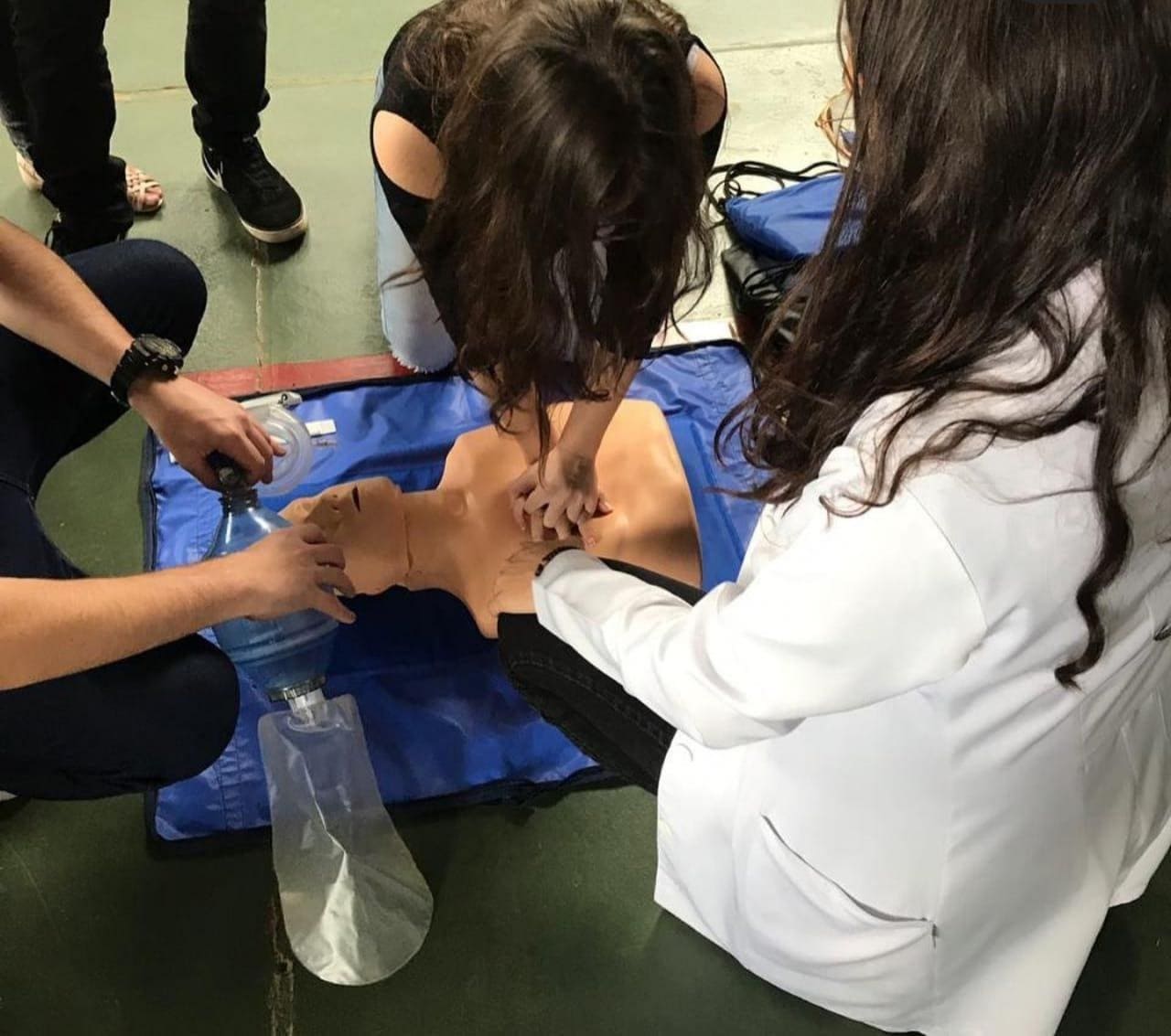 Imagem representando aluna aplicando técnica de reanimação cardipulmonar em um boneco