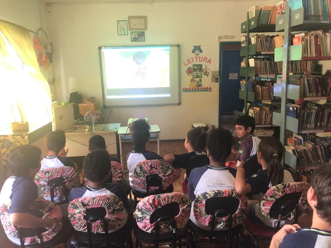 Imagem representando crianças assistindo aula dentro da biblioteca