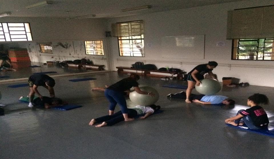 Imagem representando grupo de pessoas alongando com bola de ginástica