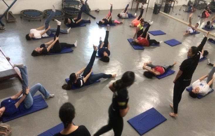 Imagem representando grupo de pessoas alongando as pernas para cima