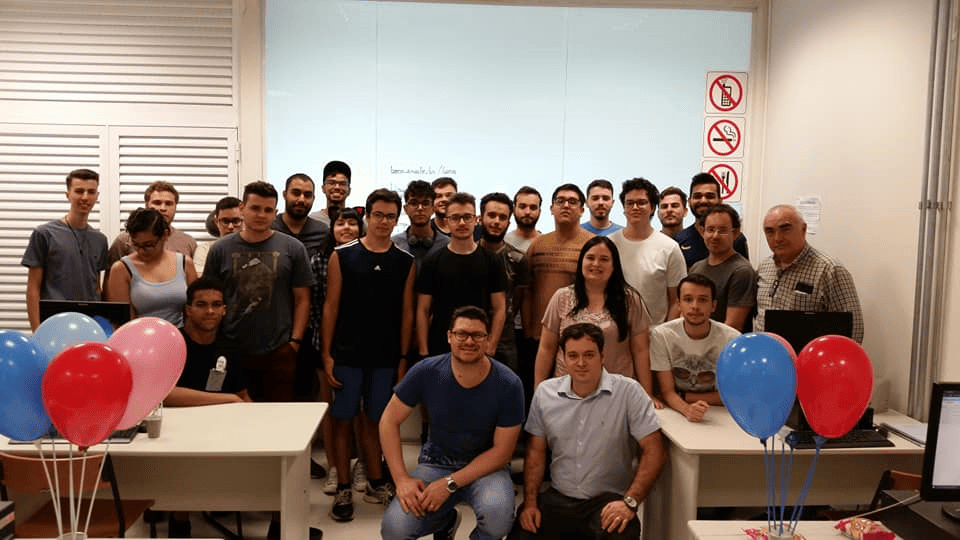 Imagem representando grupos de participantes da maratona de programação em uma sala.