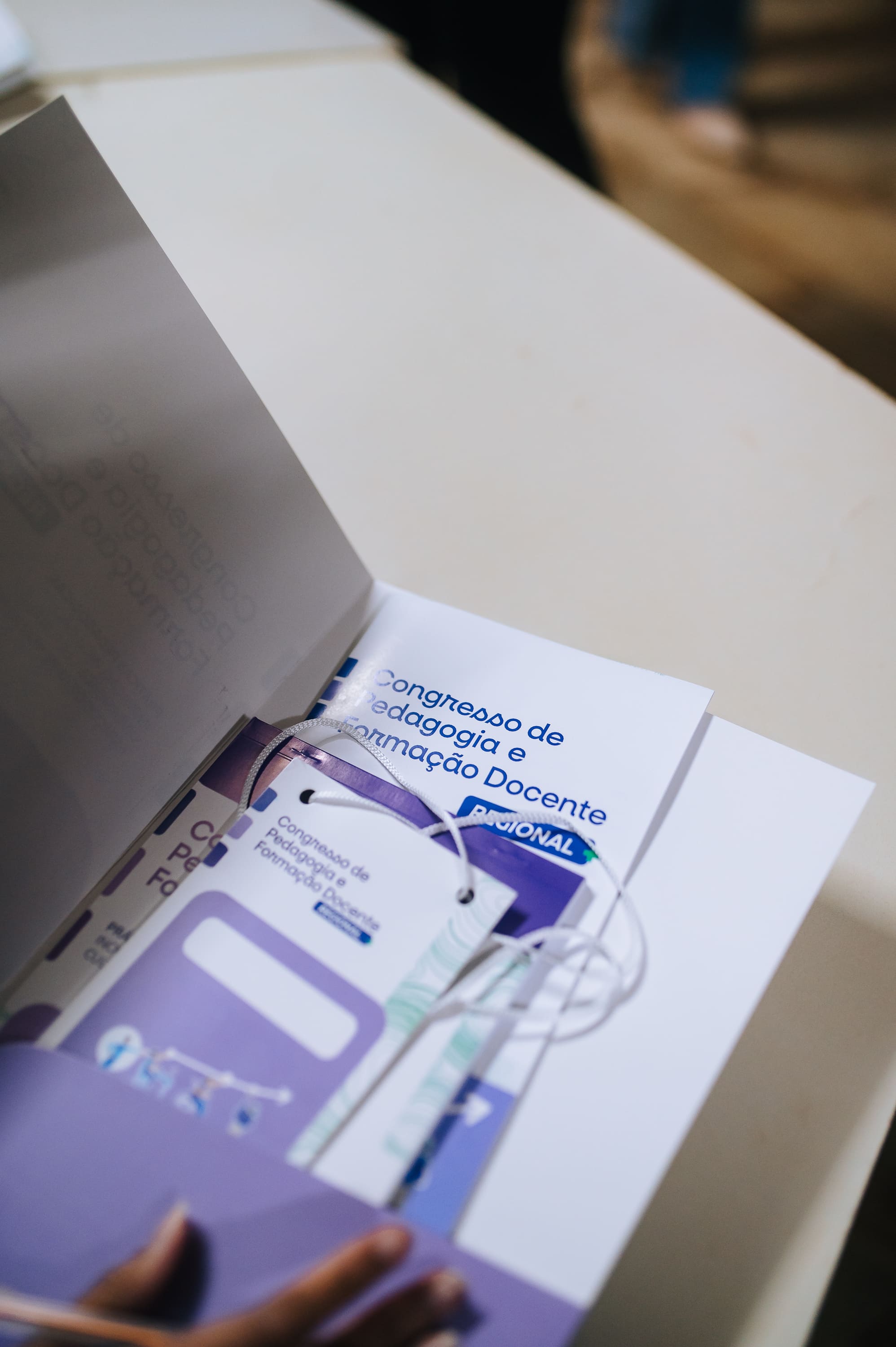 Material institucional do Congresso de Pedagogia e Formação Docente sobre mesa